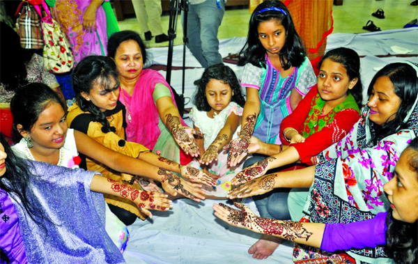 Family members of the Jatiya Press Club members flashing their palms decorated with motifs in mehedi at a mehedi festival organised by the club on its premises on Friday.