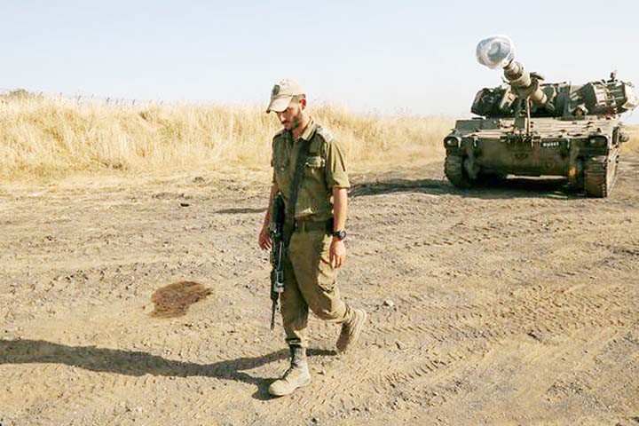 An Israeli soldier walks by mobile artillery cannon in the Israeli-annexed Golan Heights.