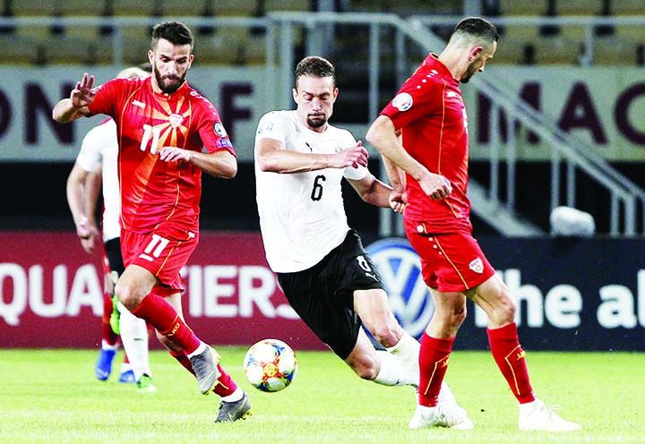 Austria's Stefan Ilsanker (center) challenges with North Macedonia's Ferhan Hasani (left) and Arijan Ademi (right) during the Euro 2020 group G qualifying soccer match between North Macedonia and Austria, at National Arena Todor Proeski in Skopje, North