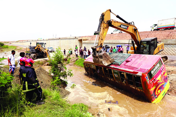 A passenger bus being lifted by excavator from the roadside ditch as it rammed into it on Dhaka-Mawa road injuring some people. This photo was taken from Keraniganj on Wednesday.