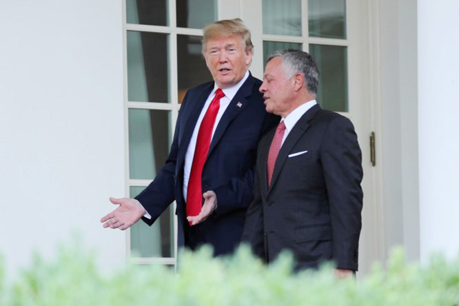 US President Donald Trump walks down the West Wing colonnade with Jordan's King Abdullah as he welcomes the King to the White House in Washington.