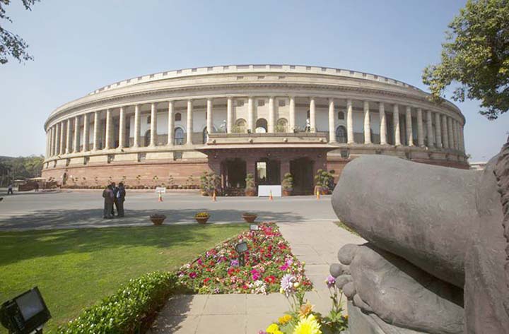 Indian Parliament building is seen from behind a Mahatma Gandhi statue, (right) in New Delhi, India.
