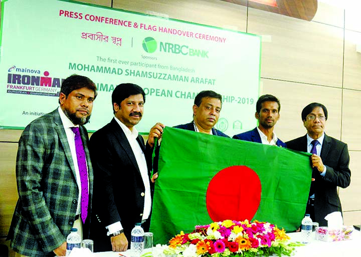 Tamal SM Parvez, Chairman of NRBC Bank Ltd, hands over the national flag to Mohammad Samsuzzaman Arafat, a participant of Ironman European Championship, Frankfurt 2019, in a media briefing at the bank's headquarters in city on Tuesday. NRBC is sponsoring