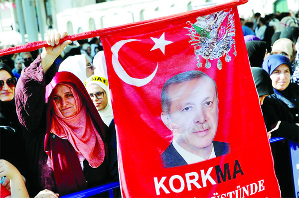 A woman holds a flag with a picture of Turkish President Tayyip Erdogan during a symbolic funeral prayer for the former Egyptian president Mohamed Mursi at the courtyard of Fatih Mosque in Istanbul, Turkey.
