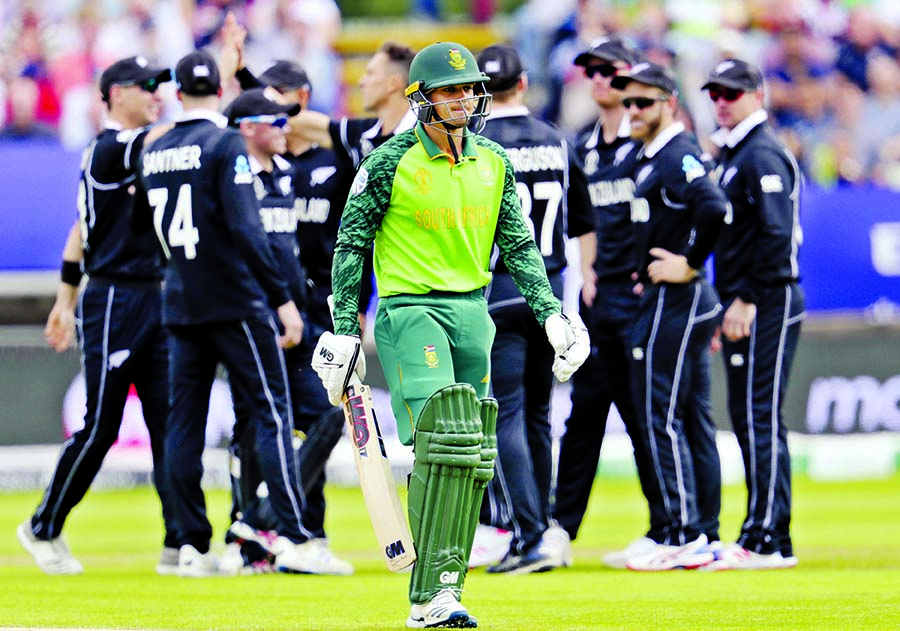 South Africa's batsman Quinton de Kock (front) leaves the pitch after is bowled by New Zealand's bowler Trent Boult for 5 runs during the ICC World Cup Cricket match between New Zealand and South Africa at the Edgbaston Stadium in Birmingham on Wednesda