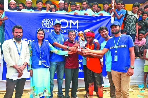 Officials of International Organisation for Migration (IOM) distributing prizes among the players of a friendly football match between locals and Rohingya people at Leda in Teknaf recently .