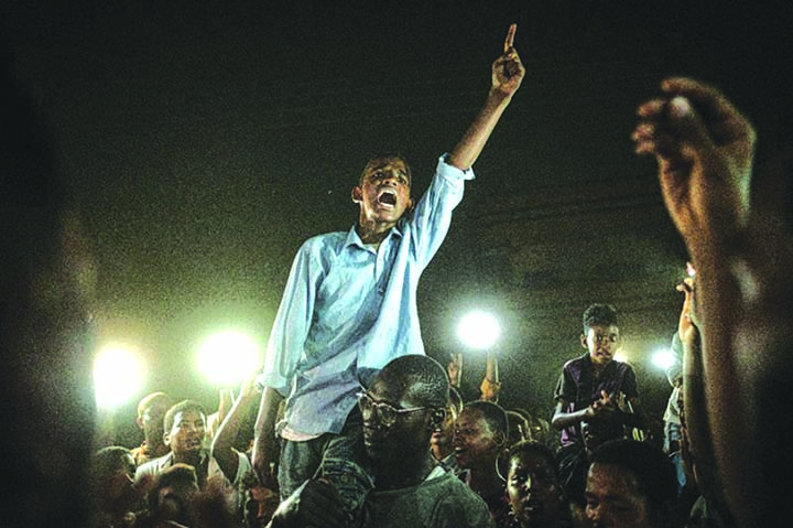 A man recites a revolutionary poem, as people gather in a southern district of Khartoum.