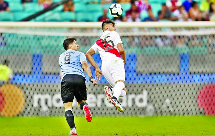 Peru's Carlos Zambrano (right) heads the ball as Uruguay's Luis Suarez looks on during a Copa America quarterfinal soccer match at the Arena Fonte Nova in Salvador, Brazil on Saturday.