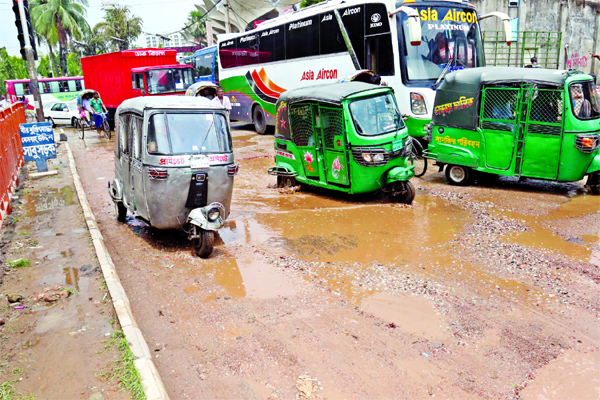 A busy road in city's Kamalapur area is in dilapidated condition as several potholes being developed and waterlogging as well following brief rains, causing sufferings to commuters. This photo was taken on Monday.