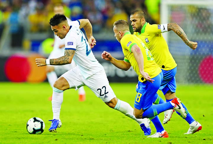Argentina's Lautaro Martinez runs with the ball as Brazil's Arthur (center) and Dani Alves challenge him during a Copa America semifinal soccer match at the Mineirao stadium in Belo Horizonte, Brazil onTuesday.