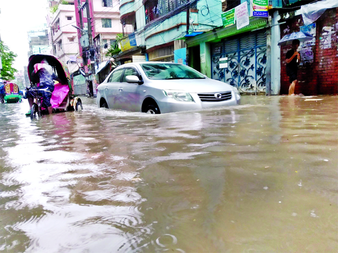Motorised vehicles and rickshaws struggle through the knee-deep stagnant rainwater as most of the city roads go under water due to rain. The snap was taken from the city's Gigatala area on Friday.
