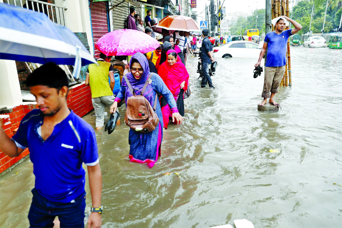 City dwellers witnessing a heavy downpour triggered by monsoon submerging many areas of the capital, where digging roads for development projects including metro rail are underway, causing sufferings to commuters. This photo was taken from city's Arambag