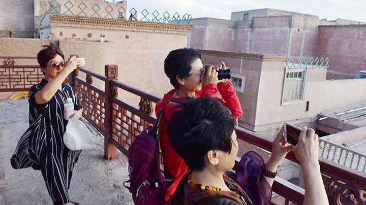 Shows tourists taking photos in the restored old city area of Kashgar, in China's Western Xinjiang region.