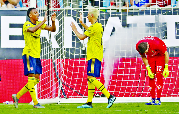 Arsenal's Joe Willoc ( left) celebrates his goal with teammate Mesut Ozil (center) against Fiorentina during the second half of an International Champions Cup soccer match in Charlotte, NC on Saturday.