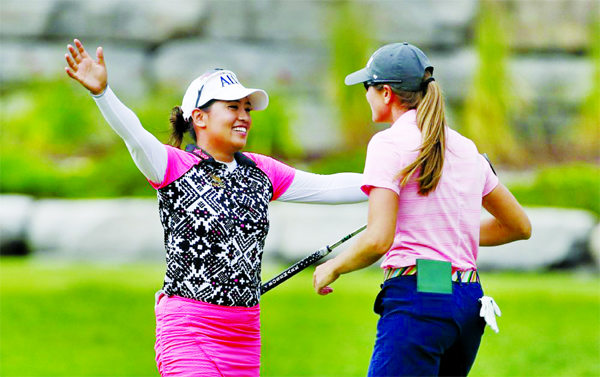 Jasmine Suwannapura of Thailand (left) hugs teammate Cydney Clanton on the 18th green after they won the Dow Great Lakes Bay Invitational golf tournament in Midland, Mich on Saturday.