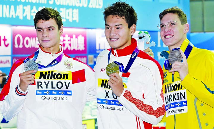 Gold medalist China's Xu Jiayu (centre) stands with silver medalist Russia's Evgeny Rylov (left) and bronze medalist Australia's Mitchell Larkin following the men's 100m backstroke final at the World Swimming Championships in Gwangju, South Korea on T