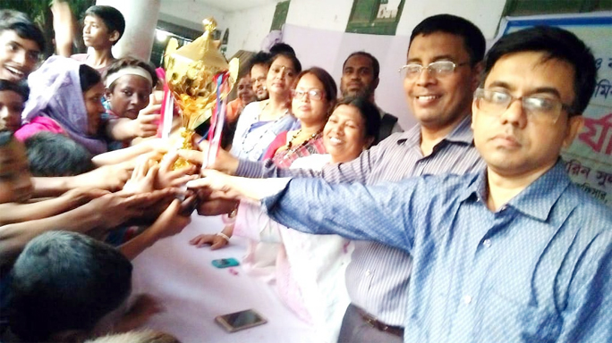 Md Zahir Uddin Chowdhury , Assistant District Primary Education Officer handing over the trophy of Bnagabandhu and Bangamata Fazilatunesa Mujib Football Tournament to champion team of National Primary School at Kotwali Thana area yesterday.