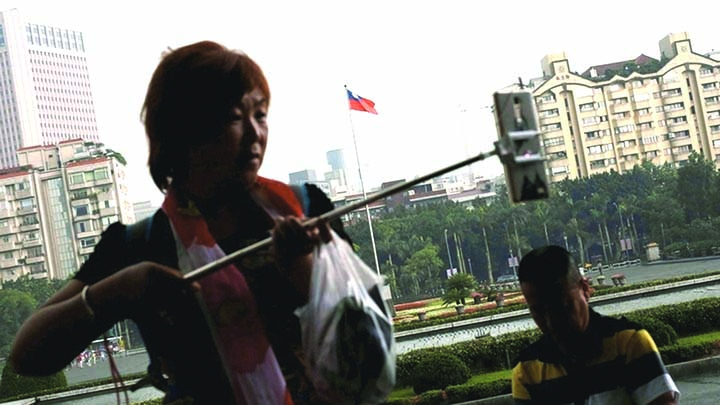 A tourist from China takes a selfie in front of a Taiwanese flag in Taipei.