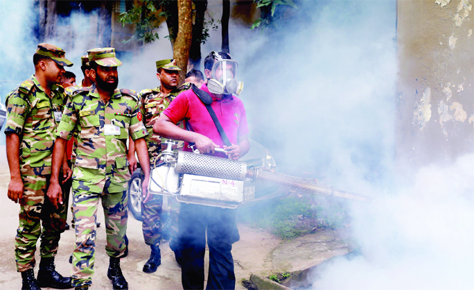 An army personnel with a fogger spraying insecticide on the side of Sultana Kamal Women's Complex at Dhanmondi in Dhaka on Saturday.