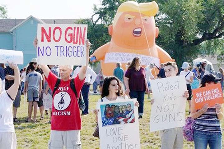 Protesters gather around a baby Trump balloon to voice their rally against gun violence and a visit from U.S. President Donald Trump following a mass shooting in Dayton.