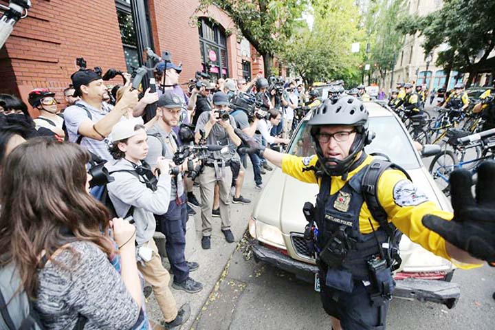 Police clear a path for a car carrying an Alt-right group leader as affiliated groups hold the End Domestic Terrorism rally in Portland, Oregon, US.