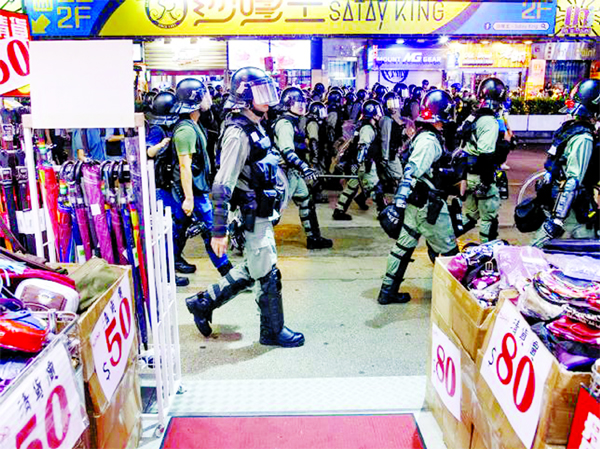 Riot police walk past a shop as they chase anti-government protesters down Nathan Road in Mong Kok in Hong Kong.