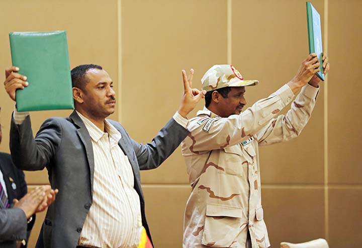 Gen. Mohammed Hamdan Dagalo, the deputy head of the military council, right, and protest leader Ahmad Rabie hold up a signed power-sharing agreement at a ceremony in the capital Khartoum, Sudan.