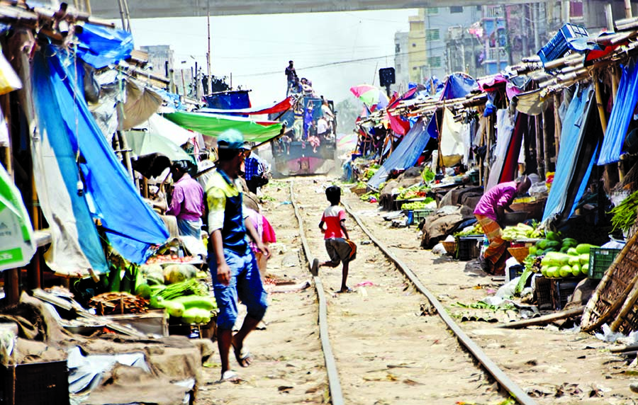 A train runs slowly as a vegetable market set up in close proximity of the railway track at Jurain in the capital despite restrictions to build structures within 50 yards of railway tracks. This photo was taken on Monday.