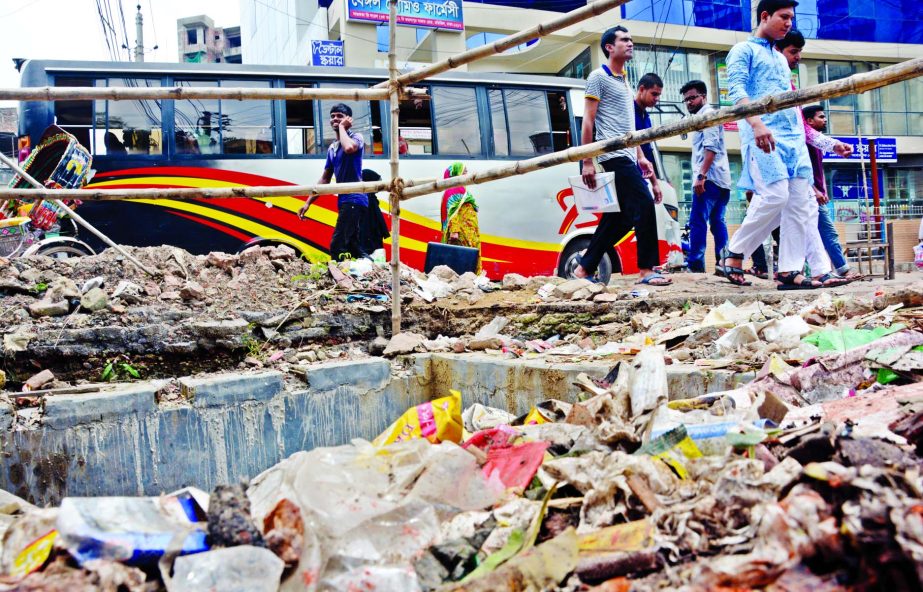 Pile of brickbats and soil in the capital's Toyenbee Circular Road in Motijheel beside the dug-up spots where the City Corporation is laying underground pipes to mitigate the water logging, causing miseries to the pedestrians in this rainy season. The ph