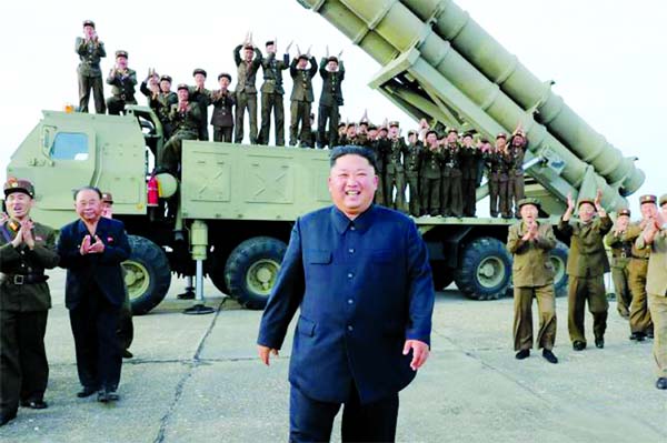 North Korean leader Kim Jong Un celebrating the test-firing of a 'newly developed super-large multiple rocket launcher' at an undisclosed location on Friday.