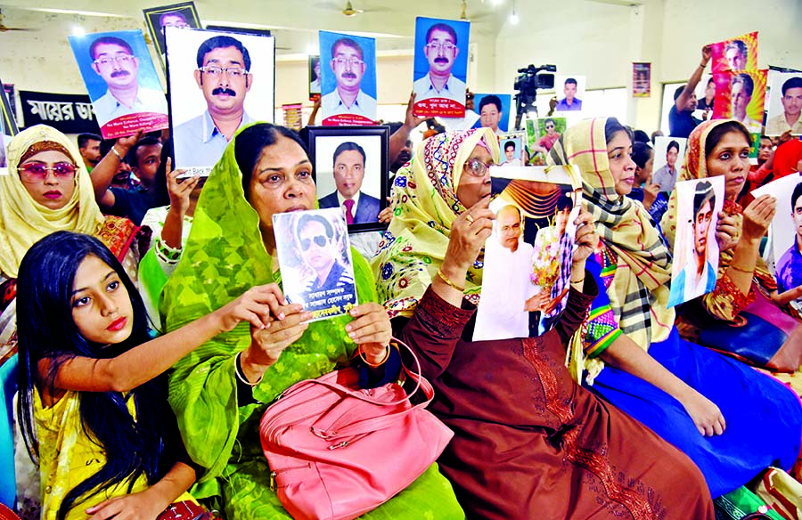 Families of enforced disappearance victims hold up photos of their loved ones at a discussion on the occasion of the International Day of the Victims of Enforced Disappearances at the Jatiya Press Club on Friday.