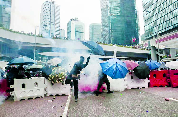 A protester throws back an exploded tear gas shell in central Hong Kong on Saturday.