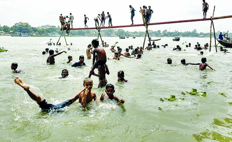 Children jumping into the Buriganga River risking their lives from a dredging pipe at Postogola area in a bid to heave a sigh of relief due to excessive heat.