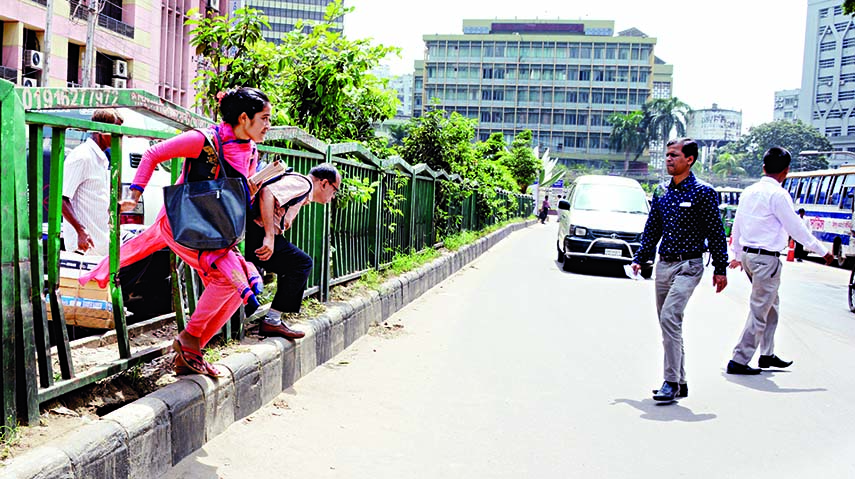 Jaywalkers crossing the road near Shapla Chattar at Motijheel in city on Tuesday, flouting road barriers and traffic regulations.