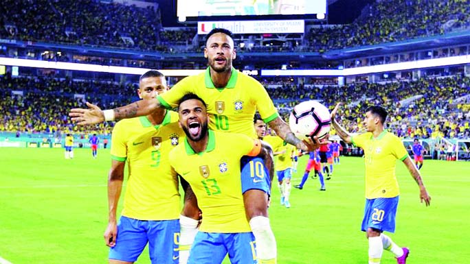 Brazil forward Neymar (10) celebrates with Dani Alves (13) and Richarlison (9) after scoring the second goal of his team during the second half of an international friendly soccer match against Colombia, in Miami Gardens on Friday.