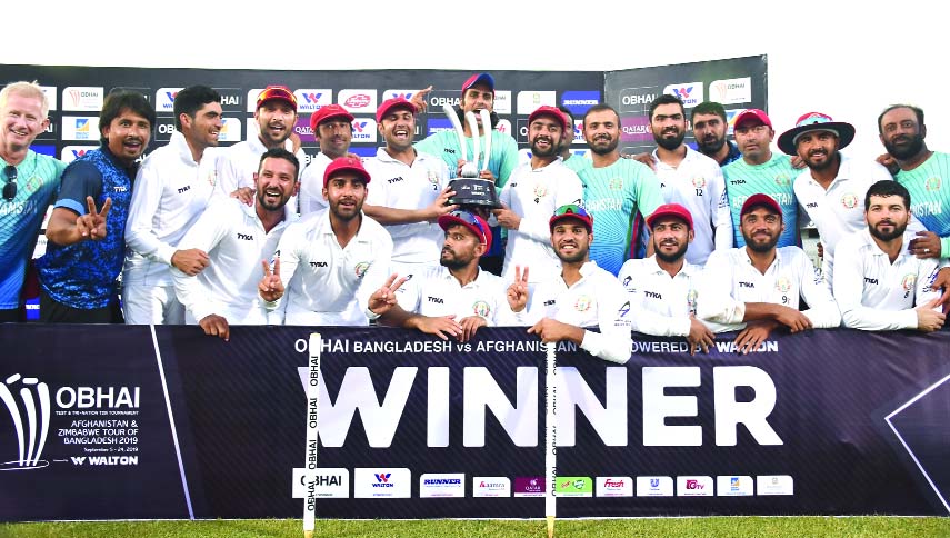 Members of Afghanistan Cricket team, the winners of the lone Test match pose with the trophy after defeating Bangladesh on the fifth and final day at the Zahur Ahmed Chowdhury Stadium in Chattogram on Monday.