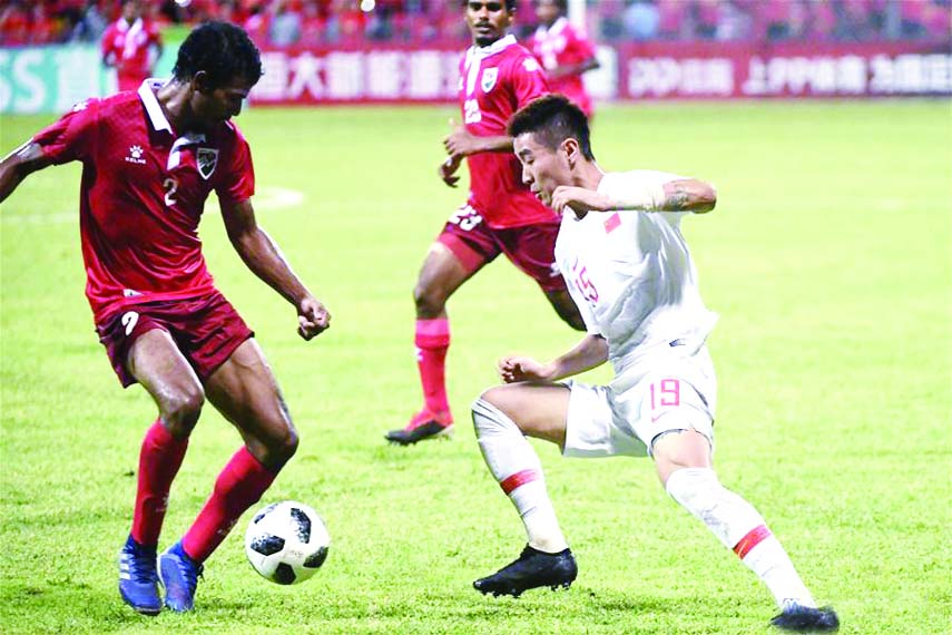 Wei Shihao (right) of China vies with Ali Samooh (left) of Maldives during the match between China and Maldives at the 2022 FIFA World Cup Asian second round qualification tournament in Male, capital of Maldives on Tuesday.