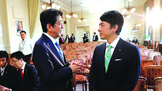 Japan's Prime Minister Shinzo Abe talks with his party's lawmaker Shinjiro Koizumi at the party lawmakers' meeting after the dissolution of the lower house was announced at the Parliament in Tokyo.