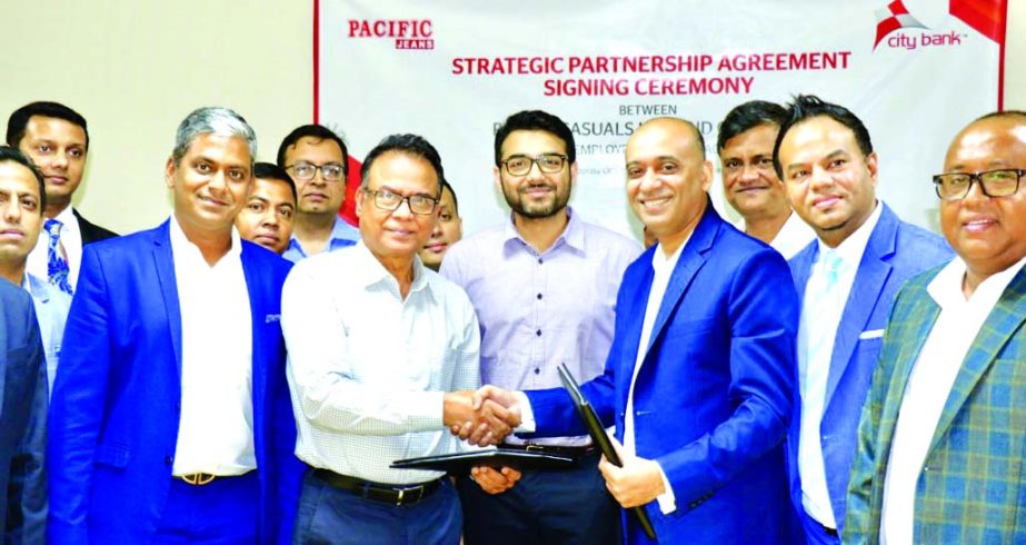 Nasir Uddin, Managing Director of Pacific Casuals Limited and Mahbubur Rahman, DMD of City Bank Limited, exchanging a strategic agreement signing document at Pacific Jeans head office at CEPZ in Chattogram on Wednesday. Other senior officials from both si