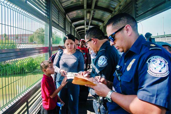 Customs and Border Patrol officials checking the papers of a Venezuelan family seeking asylum at the border between Laredo, Tex, and Nuevo Laredo, Mexico.