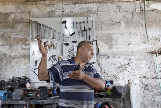 Palestinian Barhoum Saleh gives an interview at his roadside mechanic shop, near the West Bank Israeli settlement of Elkana, west of Qalqiliya.