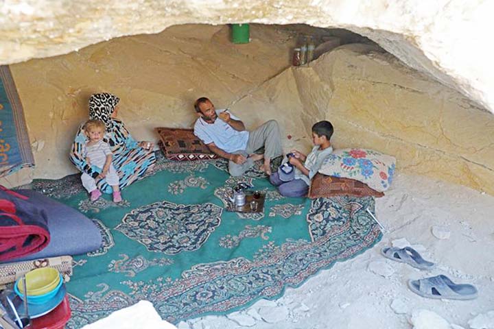 Abu Ahmad, a displaced Syrian from Termala sits with his family inside a cave he dug for shelter near the Syria-Turkey border.