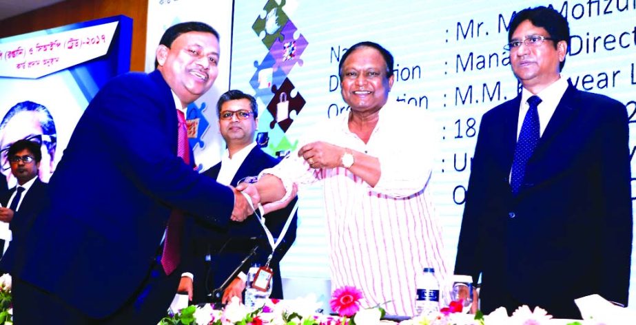 Mofizul Islam, Managing Director of A M Knitwear Limited, receiving the CIP card from Commerce Minister Tipu Munshi at a function held at a hotel in the city on Wednesday. Former Commerce Minister Tofail Ahmed and senior officials were also present.