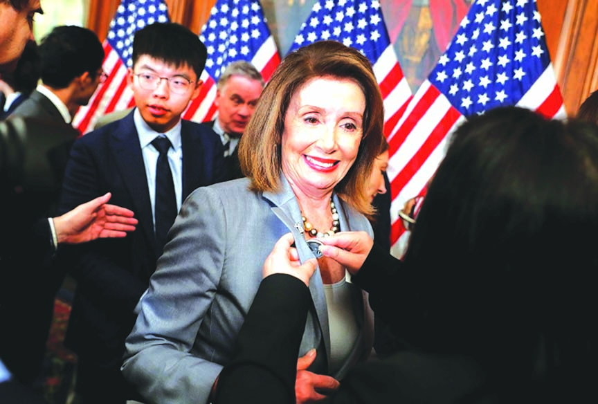 US House Speaker Nancy Pelosi is given a lapel pin by a Hong Kong activist following a news conference on human rights in Hong Kong on Capitol Hill in Washington, on Wednesday. Behind Pelosi is Hong Kong activist Joshua Wong.