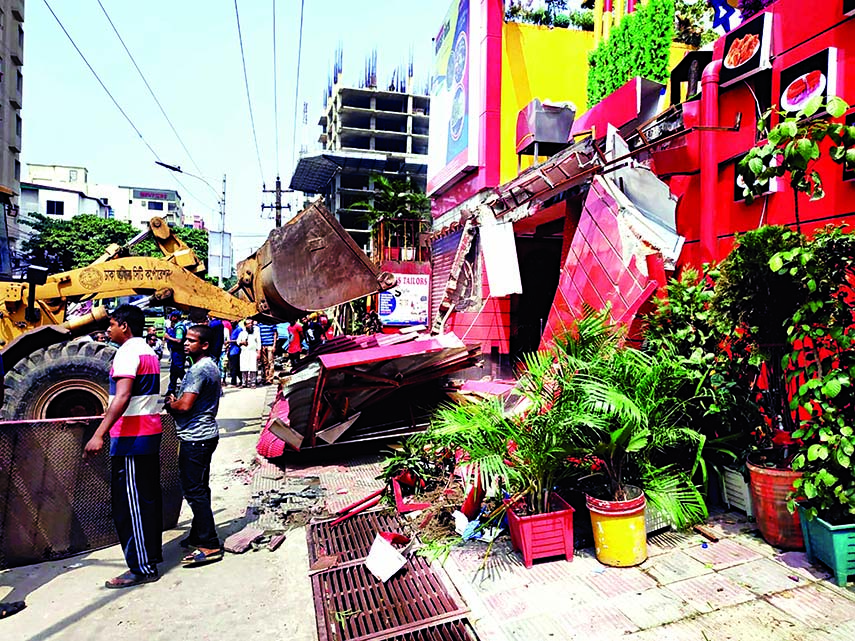 A DSCC bulldozer knocks down structures set up at Shahjahanpur Railway Colony in city on Sunday.