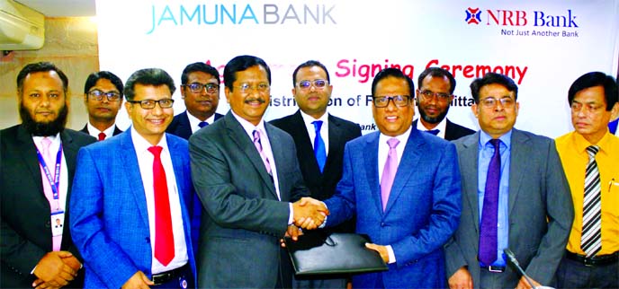 Md. Mehmood Husain, CEO of NRB Bank Limited and Shafiqul Alam, CEO of Jamuna Bank Limited, exchanging an agreement signing document for the distribution of Foreign Remittance at Jamuna Bank's head office in the city on Monday. Senior officials from both