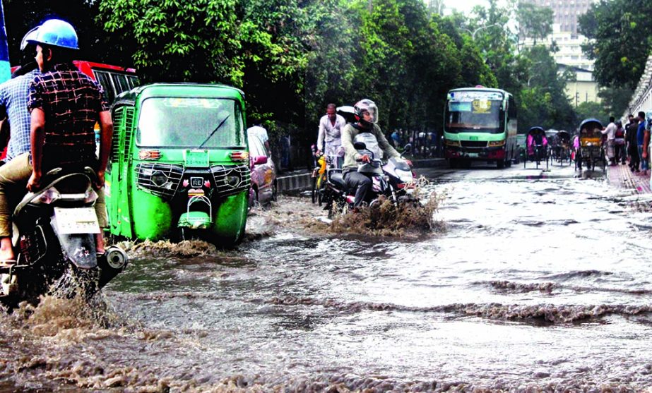Vehicles wading through the ankle deep rain water that submerged the busy road in Gulistan due to drainage mismanagement. This photo was taken on Saturday.
