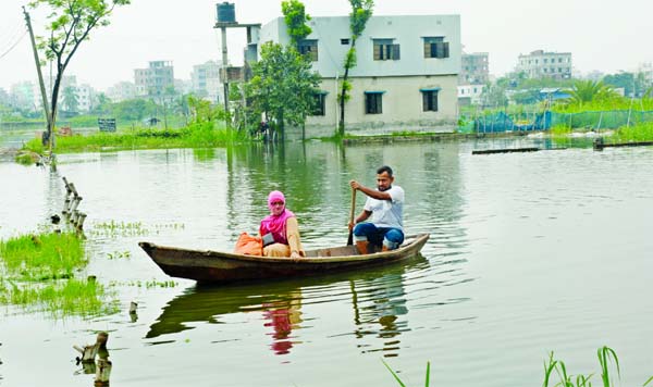 Heavy rainfall during the last few days has flooded some areas inside the Dhaka-Narayanganj-Demra (DND) dam causing immense sufferings to the people. This photo shows that a young woman takes a ride on a boat to cross the waterlogged area on Thursday.
