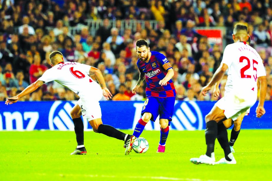 Barcelona's Lionel Messi (center) runs with the ball next to Sevilla defenders during Spanish La Liga soccer match between Barcelona and Sevilla at the Camp Nou stadium in Barcelona on Sunday.