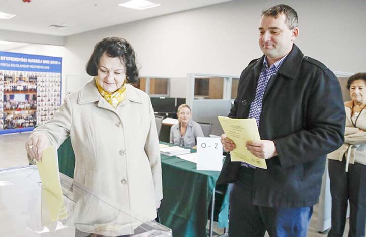 Ewa Cieply places her vote into the ballot box next to her son Marek Cieply on Saturday in Mount Prospect, Illinois, one day before parliamentary elections in Poland.
